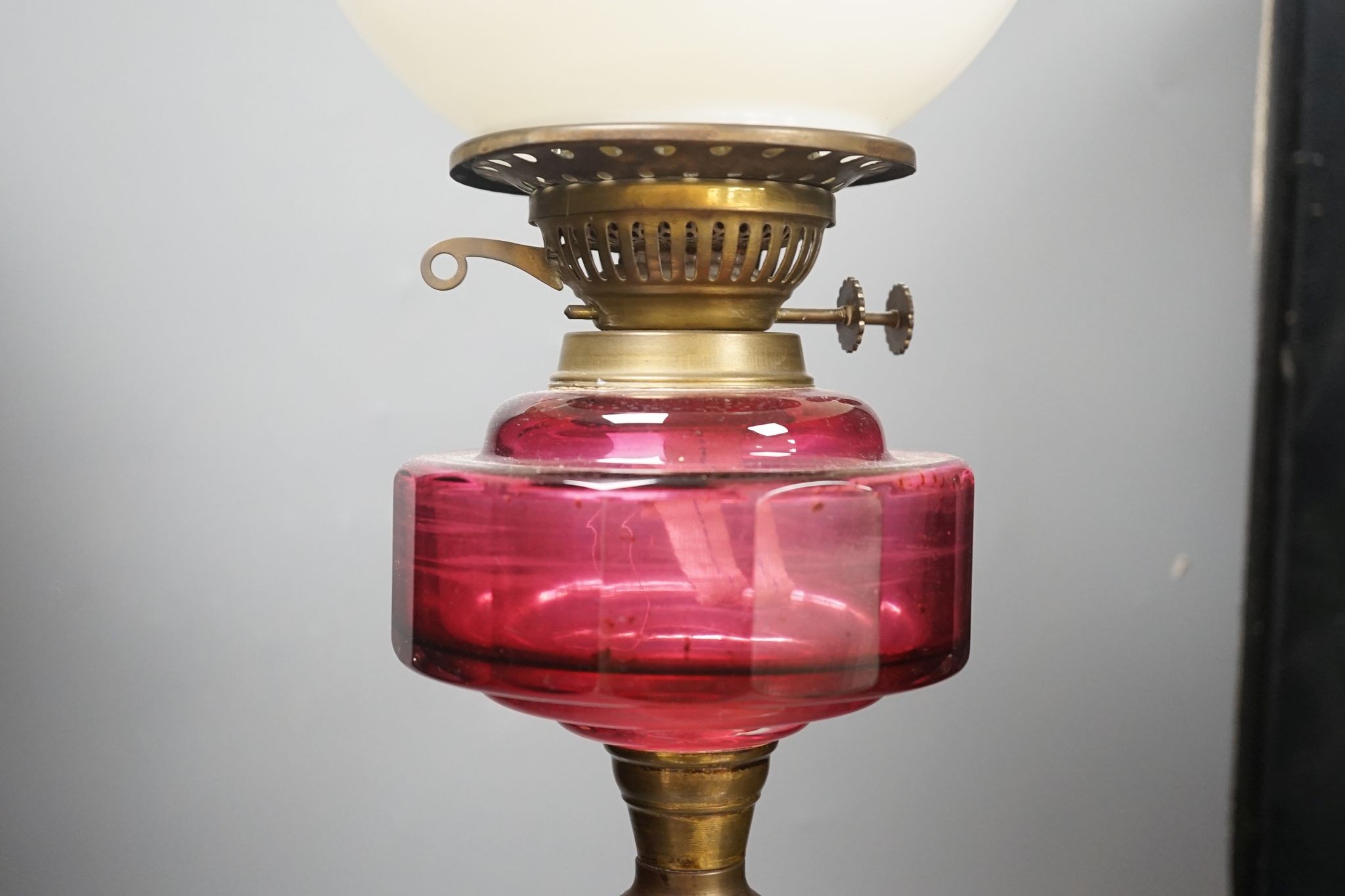 A Victorian brass and cranberry glass oil lamp, 78 cms high.